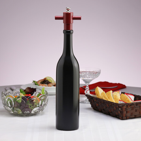 A Chef Specialties Chateau wine bottle salt mill on a table next to a bowl of food.