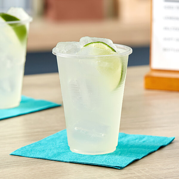 A translucent Choice plastic cup with ice water and a lime slice on a blue napkin.