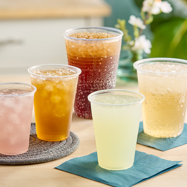 A group of Choice translucent plastic cups filled with different colored drinks on a table.