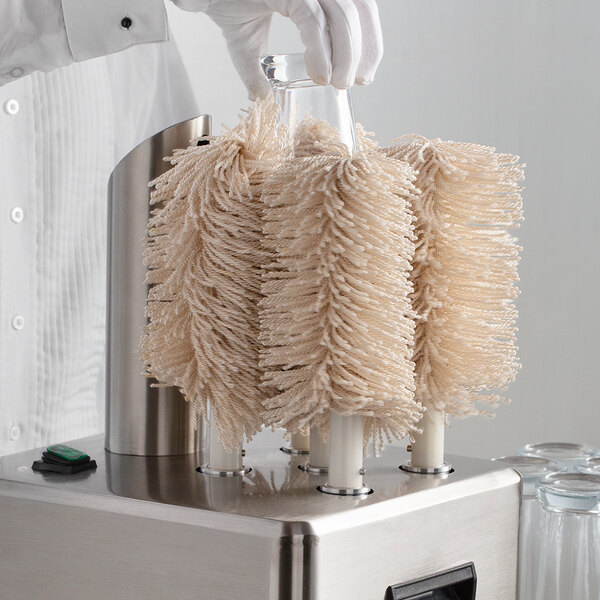 A person in white gloves uses a Noble Products glass washing machine.