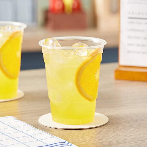 Two Choice translucent plastic cups of lemonade on a table.