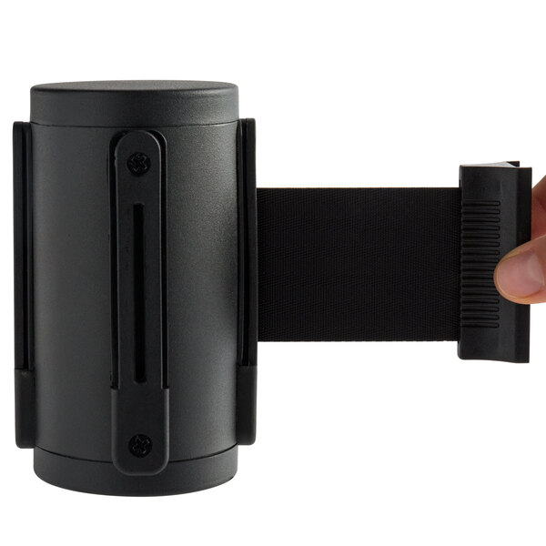 A hand holding a black wall-mounted stanchion head.