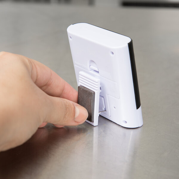 A hand holding a small white Taylor 5828 kitchen timer.