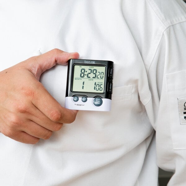 A person holding a Taylor digital clock.