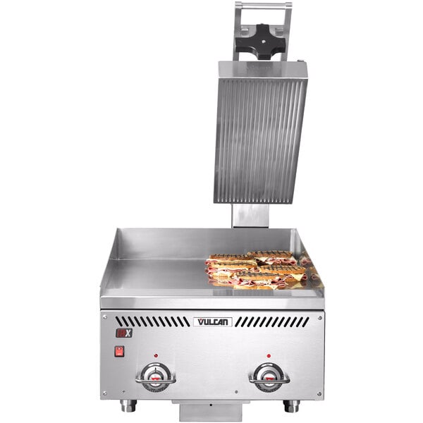 A Vulcan countertop electric griddle with grooved steel plates open with sandwiches cooking.