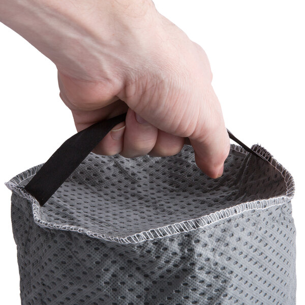 A person holding a black cloth bag with a black strap.