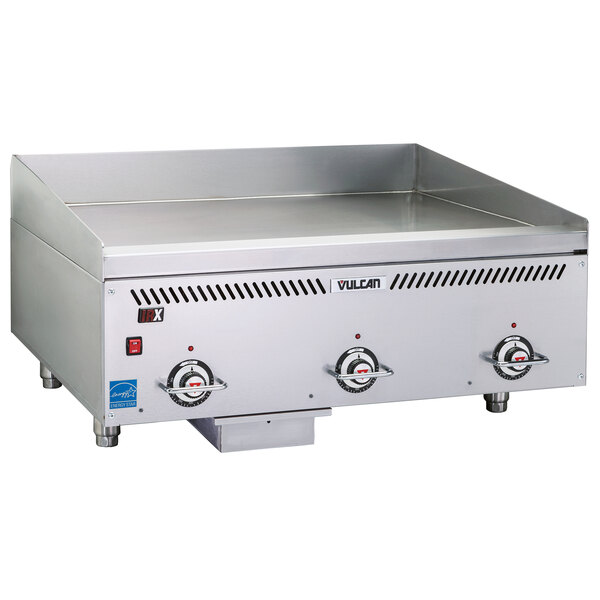 A stainless steel Vulcan commercial griddle on a counter with knobs.