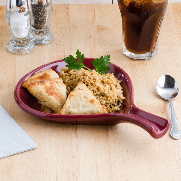 A plate of food served in a Tuxton fry pan server on a table with a glass of brown liquid.