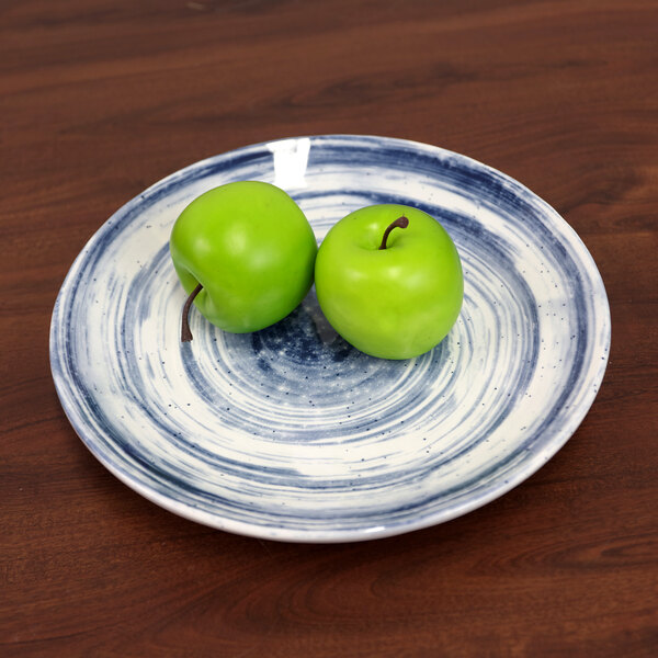 An Elite Global Solutions round navy melamine plate with two green apples on it.