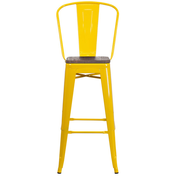A yellow metal bar stool with a wooden seat.