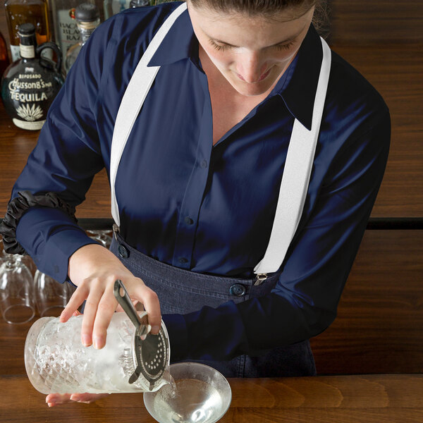 A woman pouring a drink into a glass using a can opener.