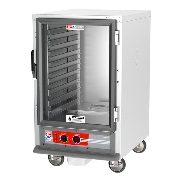 A white metal Metro C5 heated holding cabinet with a clear glass door on wheels.