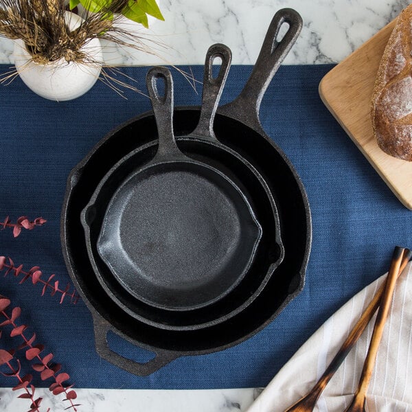 Three cast iron skillets nested over blue backdrop