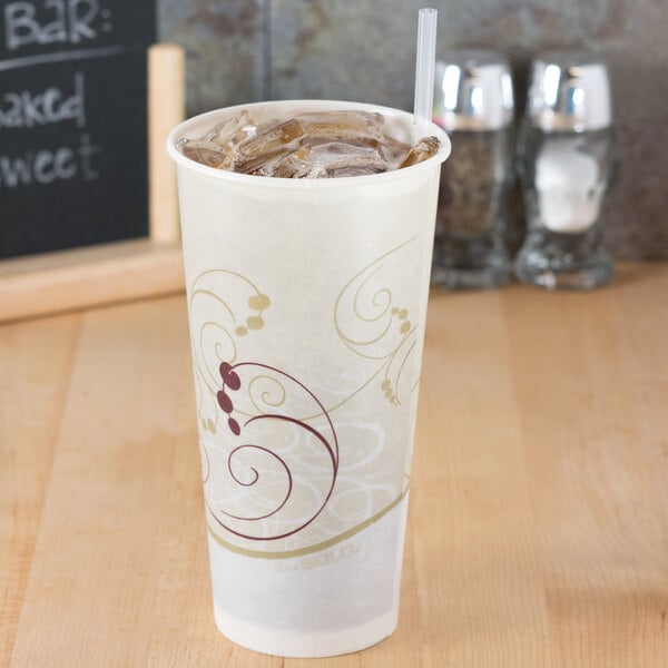 A Solo wax treated paper cold cup filled with iced coffee on a table with a straw.