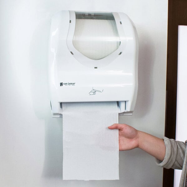 A hand reaching out to a San Jamar Hybrid Summit paper towel dispenser.