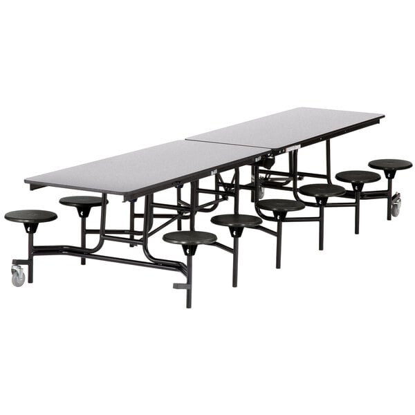 A long rectangular black table with black stools on it.