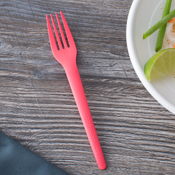 A coral Eco-Products compostable plastic fork on a plate with a lime wedge.