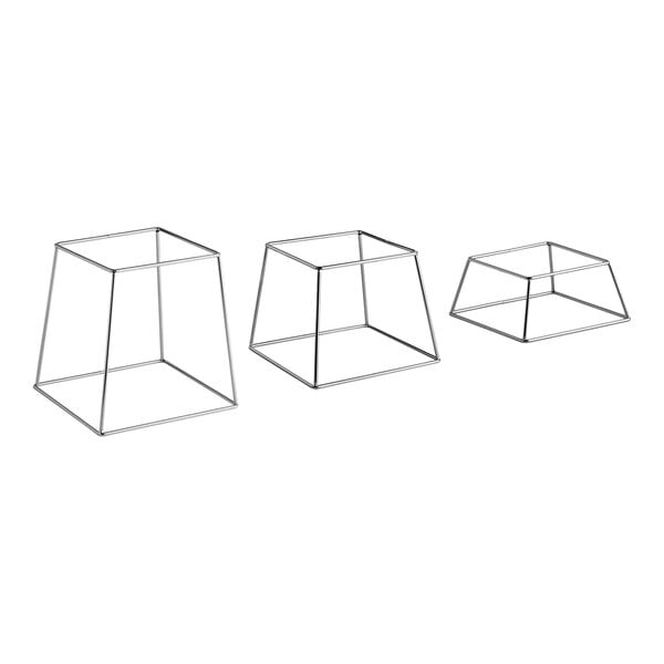 A set of three square stainless steel metal display stands in varying heights.
