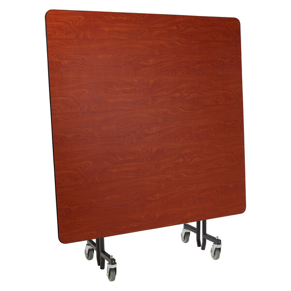 A rectangular wood table with a T-shaped wood panel on wheels.