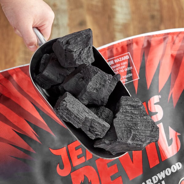Lump charcoal being scooped out of a bag