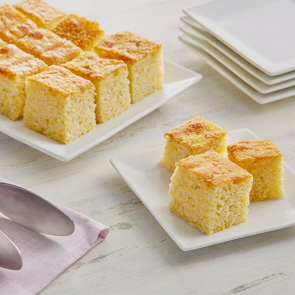 A plate of yellow cornbread squares on a white plate.