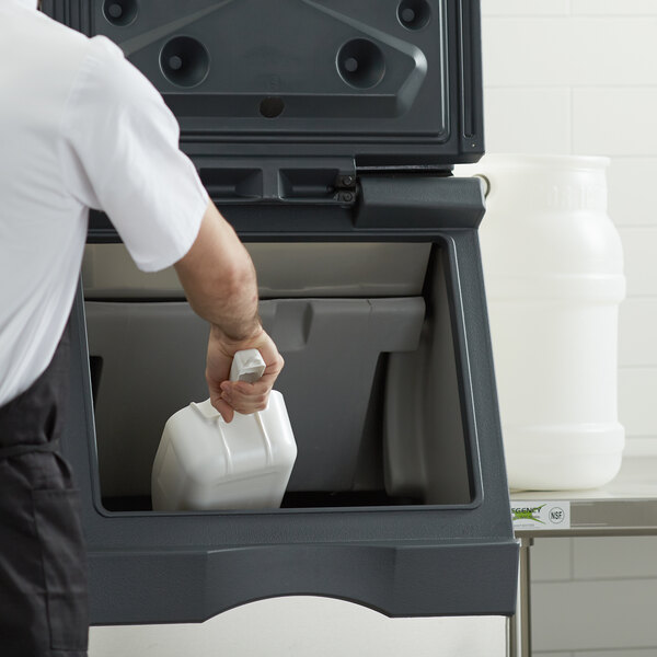 A man using a white jug to pour water into a white container on a Scotsman air cooled ice machine.
