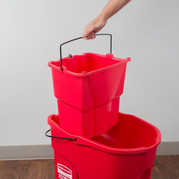 hand pulling handle of red Rubbermaid dirty water bucket