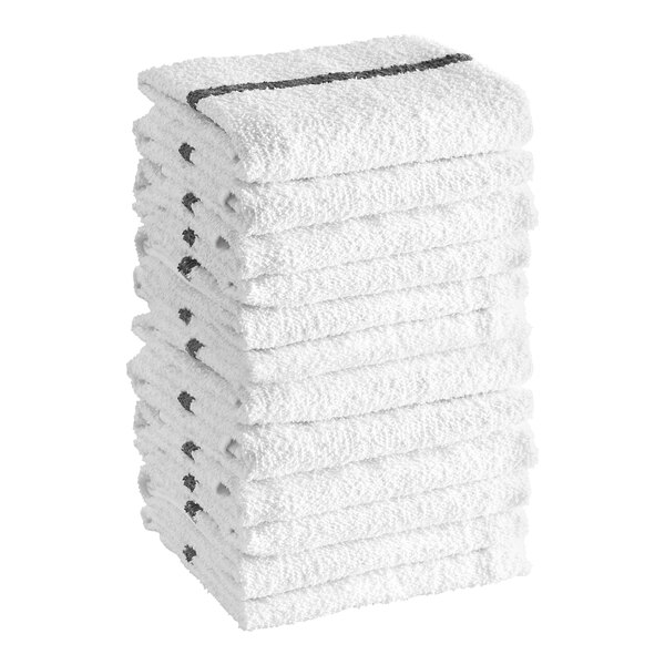 A stack of twelve white textured towels, each with a black stripe near one edge.