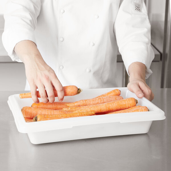 A person picking up carrots in a Rubbermaid food storage box.