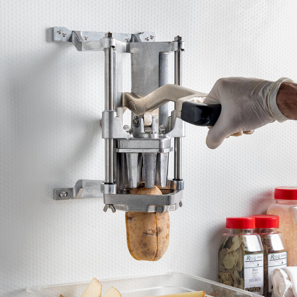 A person using a Nemco Easy FryKutter to cut potatoes into wedges.