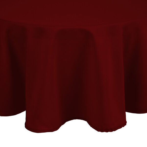 An Intedge burgundy polyester round table cover on a table.