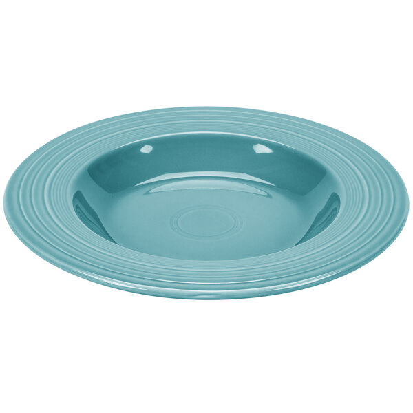 A close-up of a Fiesta turquoise pasta bowl with a white interior and blue rim.