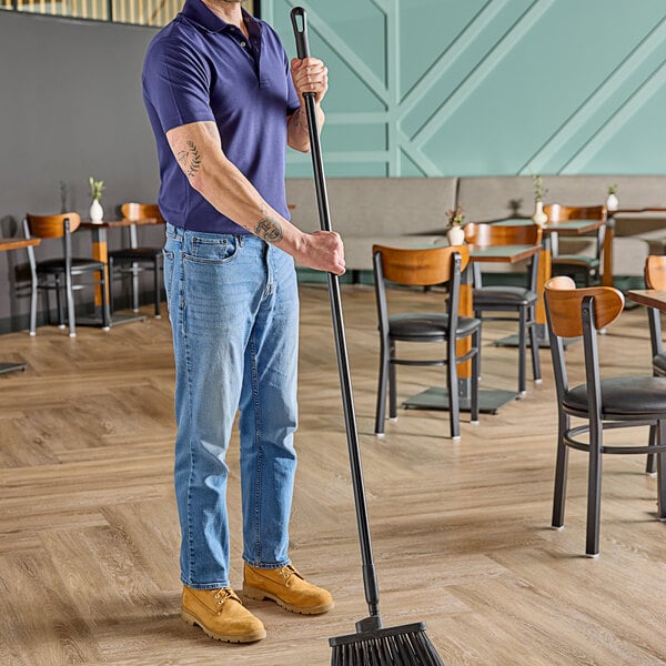 A man holding a Carlisle black threaded fiberglass broom handle.