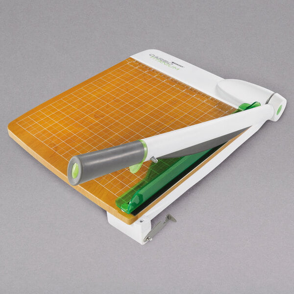 A Westcott paper cutter with a white handle and a green blade on a surface.