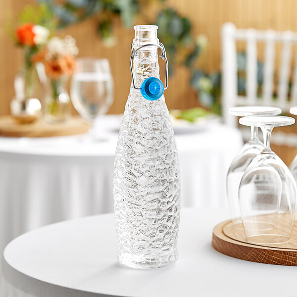 A Libbey glass bottle with a blue wire bail lid on a table.