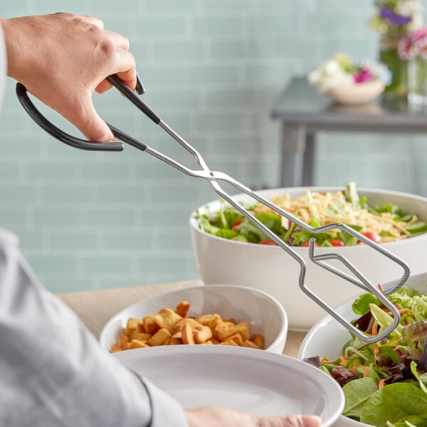 A person using Vollrath scissor tongs to serve salad