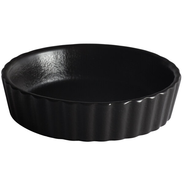 A black round Acopa Keystone stoneware dish with a wavy edge.