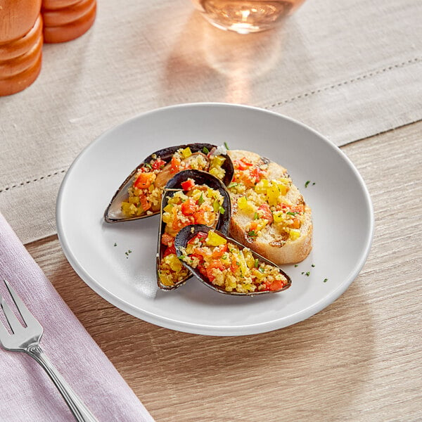 An Acopa matte white stoneware plate with mussels and rice on a table.