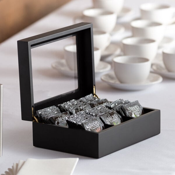 A black wood tea chest with a window containing tea bags.