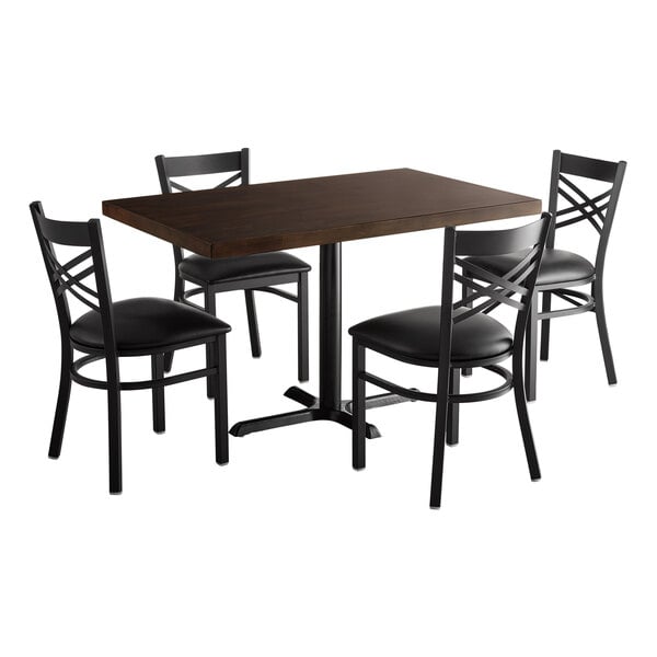 A Lancaster Table & Seating wood butcher block dining table and chairs with black cushions.