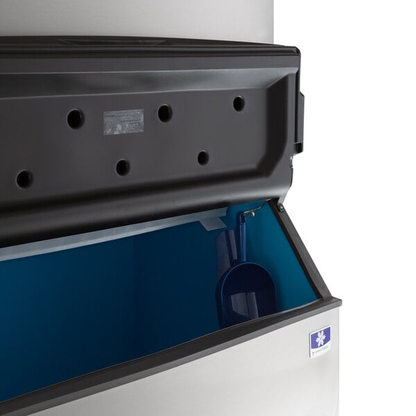 A black and white Manitowoc air cooled ice machine bin with a blue lid.