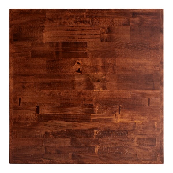 A close up of a Lancaster Table & Seating wood butcher block table top with a mahogany finish.