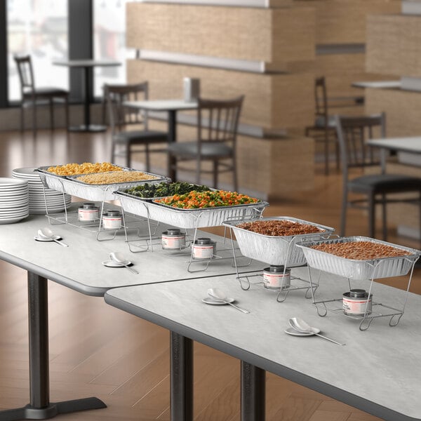 A buffet table with metal containers of food on wire stands with flames underneath.
