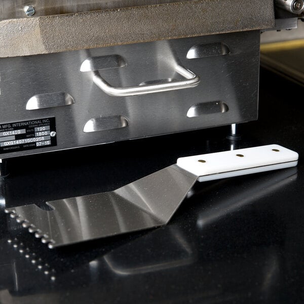A Star CG-S grooved panini grill spatula on a black counter.