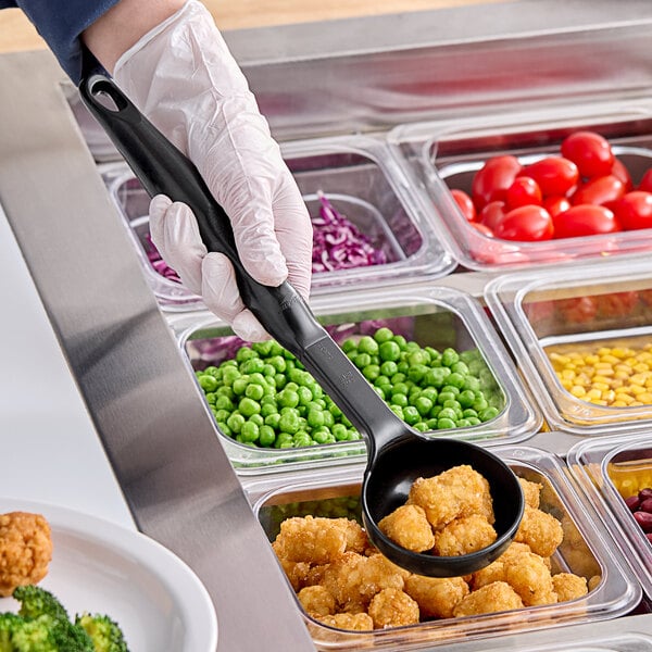 A person using a black Vollrath Spoodle to serve food at a salad bar.
