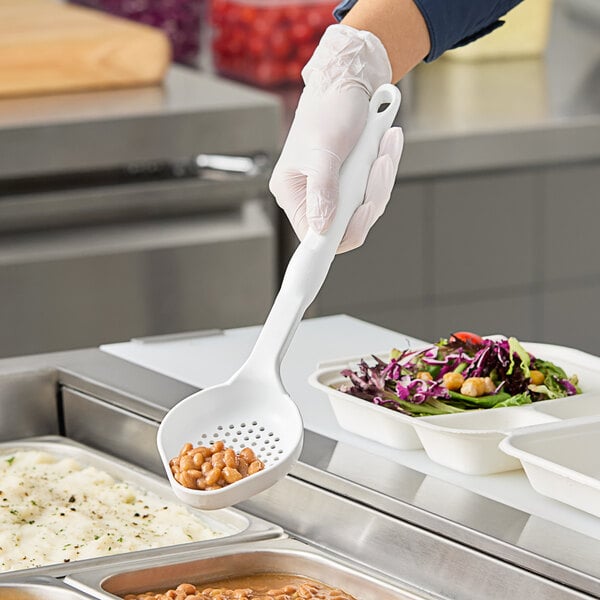 A person in gloves holding a white Vollrath Spoodle over food in a white container.