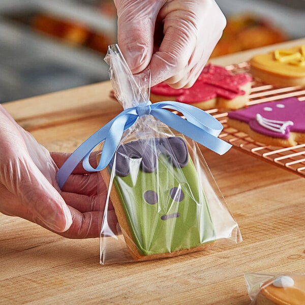 A hand wrapping a Frankenstein cookie in a LK Packaging plastic bag.