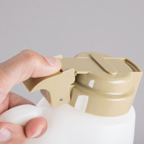 A person holding a Tablecraft plastic sauce dispenser with assorted tops.