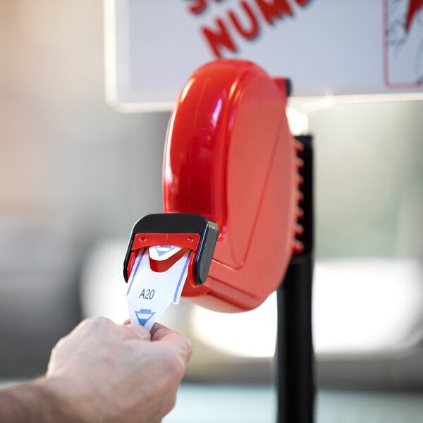 A hand holding a Garvey My Turn blue 3-digit ticket in a red machine.