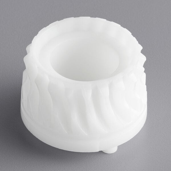 A white plastic object with a circular pattern and a hole in the center.